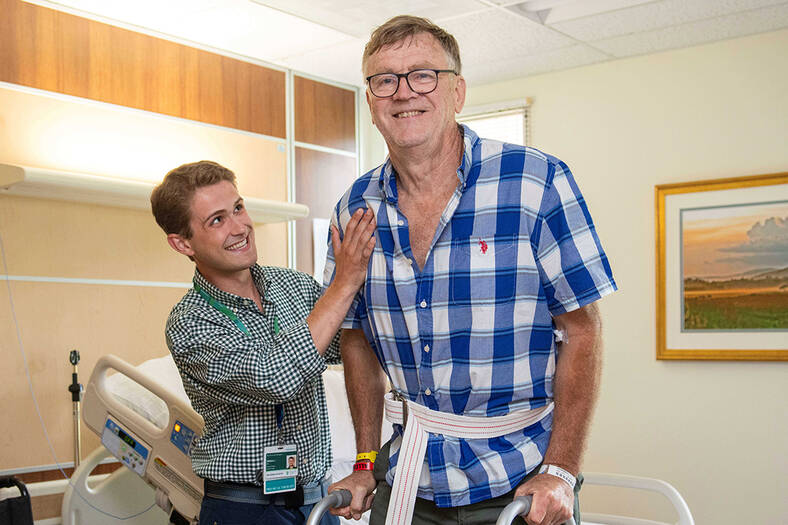 A physical therapist helping a patient stand with use of a walker